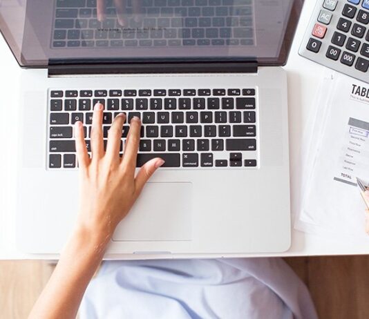 overhead-view-of-person-calculating-budget-near-a-keyboard
