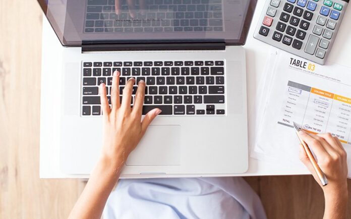 overhead-view-of-person-calculating-budget-near-a-keyboard overhead-view-of-person-calculating-budget-near-a-keyboard