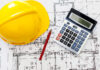Hardhat calculatorand pencil on blueprints for job costing