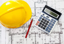 Construction Job Costing: How to Track Labour Costs Across Projects More Clearly Hardhat calculatorand pencil on blueprints for job costing