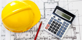 Hardhat calculatorand pencil on blueprints for job costing