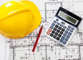 Construction Job Costing: How to Track Labour Costs Across Projects More Clearly Hardhat calculatorand pencil on blueprints for job costing