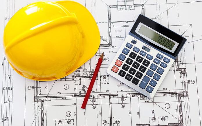 Hardhat-calculator-and-pencil-on-blueprints-for-job-costing Hardhat calculatorand pencil on blueprints for job costing