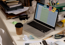 Messy desk with complex HR spreadsheet open on laptop.