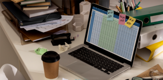 Messy desk with complex HR spreadsheet open on laptop.