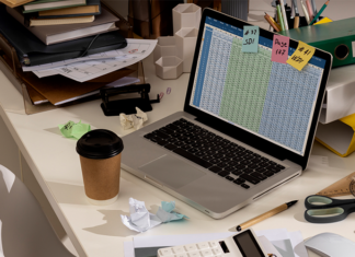 Messy desk with complex HR spreadsheet open on laptop.
