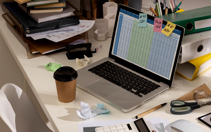 complex-hr-spreadsheet-data-management-laptop Messy desk with complex HR spreadsheet open on laptop.
