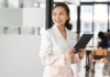 7 Workforce Management Tasks SMEs Can Handle More Efficiently Smiling HR professional using tablet for efficient workforce management.