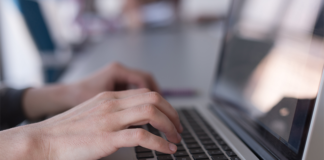 Hands typing accurate payroll data on a laptop keyboard.